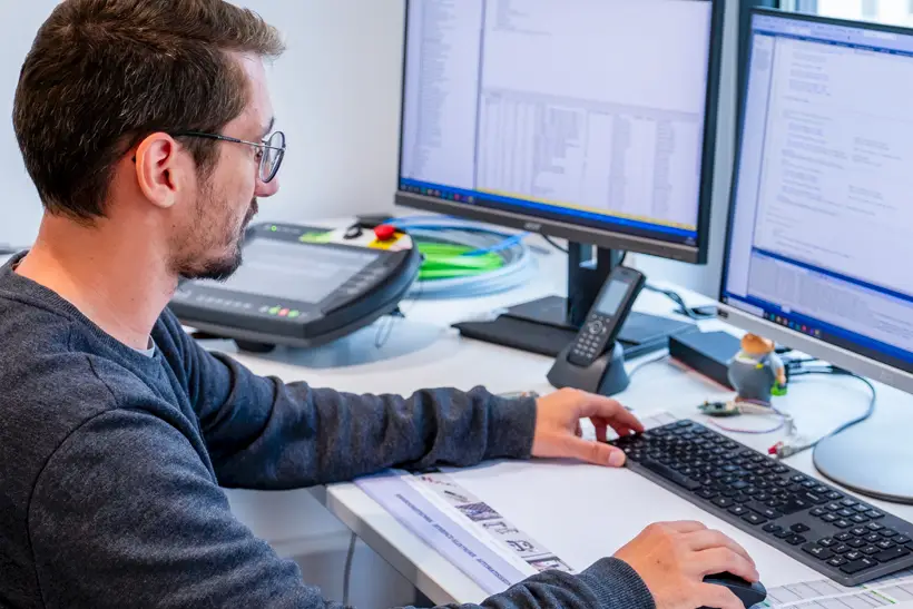 Ein Elektronik Ingenieur sitz am Schreibtisch und programmiert